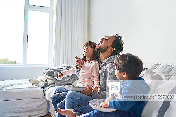 Playful family eating popcorn on sofa