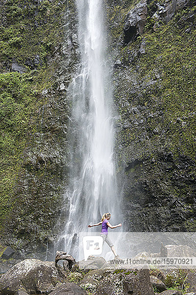 Wanderer  der entlang des berühmten Kalalau-Trails vor einen Wasserfall springt  entlang der Na Pali-Küste von Kauai  Kauai  Hawaii  Vereinigte Staaten von Amerika  Nordamerika