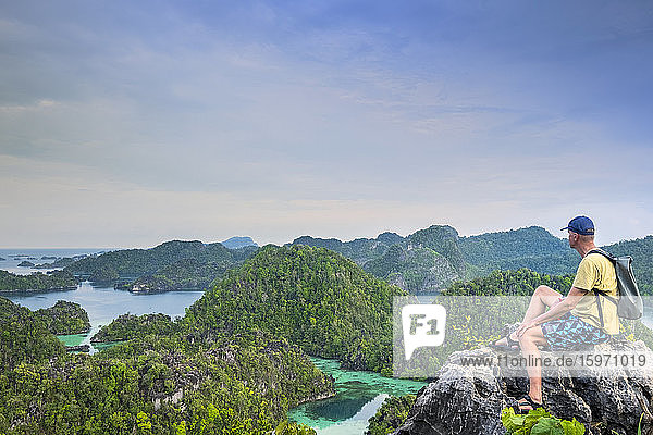 A tourist looking out over a bay of islands from Harfat mountain  Spice Islands  West Papua  Indonesia  Southeast Asia  Asia