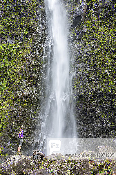 Wanderer bewundert einen Wasserfall entlang des berühmten Kalalau-Trails  entlang der Na Pali-Küste von Kauai  Kauai  Hawaii  Vereinigte Staaten von Amerika  Nordamerika