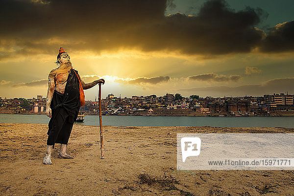 An Indian Hindu Sadhu (saint) on the banks of holy river of Ganges and Varanasi city in the background  Varanasi  Uttar Pradesh  India  Asia