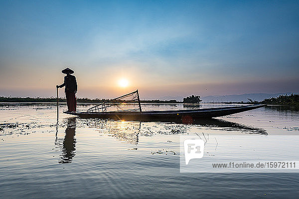 Fisherman at Inle Lake with traditional Intha conical net at sunset  fishing net  leg rowing style  Intha people  Inle Lake  Shan state  Myanmar (Burma)  Asia