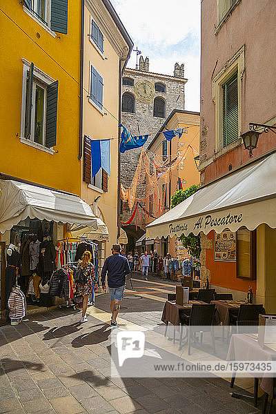 Blick auf Cafés und Besucher auf einer schmalen Straße an einem sonnigen Tag  Gardasee  Gardasee  Provinz Verona  Venetien  Italienische Seen  Italien  Europa