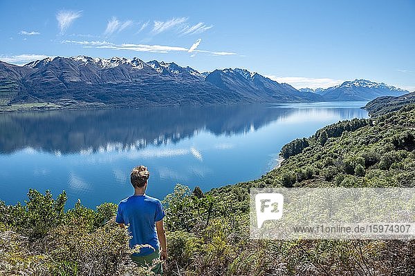 Young man looking over Lake Wakatipu  mountains reflected in the lake  Otago  South Island  New Zealand  Oceania