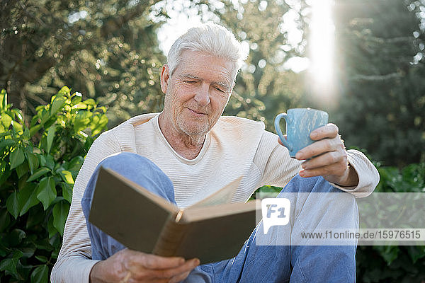 Älterer Mann liest ein Buch im Freien