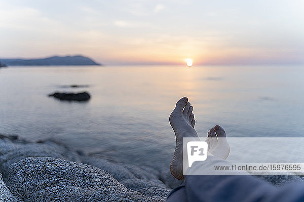 Spanien  Costa Brava  Beine einer am Strand liegenden Frau bei Sonnenaufgang