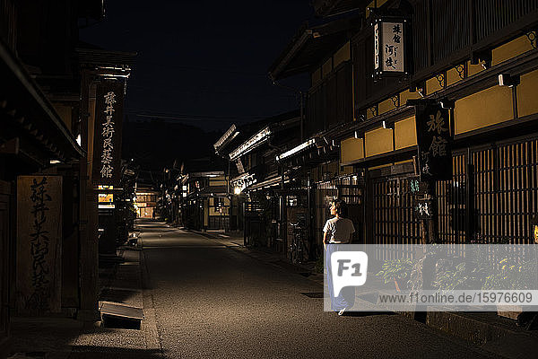 Japan  Takayama  Einsame Frau geht zwischen Reihen traditioneller japanischer Häuser bei Nacht