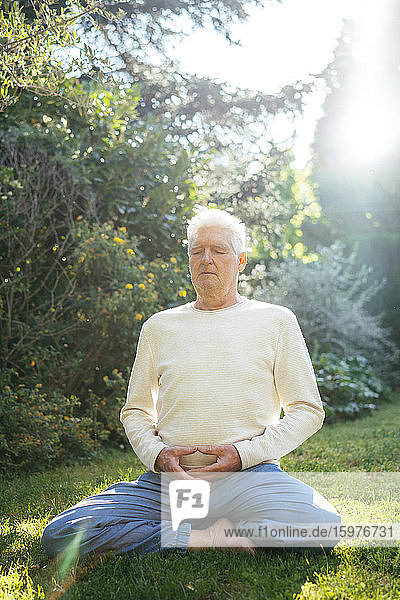 Älterer Mann meditiert im Garten