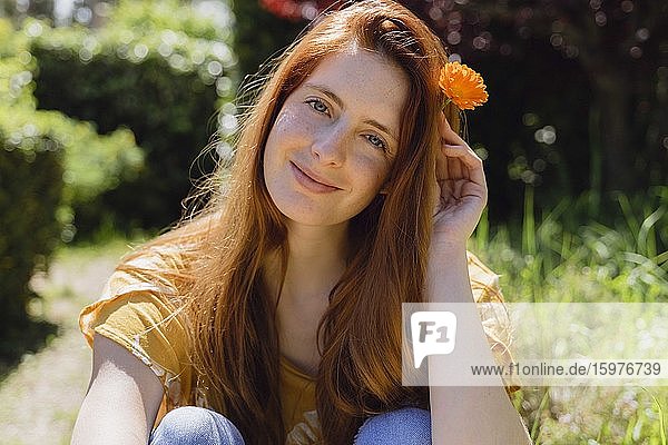 Porträt einer lächelnden jungen Frau mit Blume im Haar