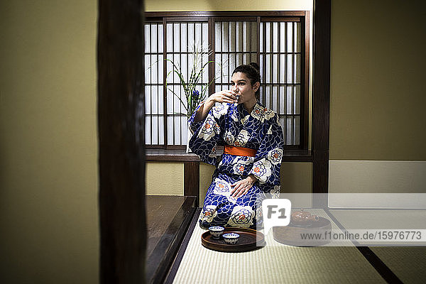 Japan  Junge Frau im traditionellen Kimono trinkt Tee in einem Ryokan
