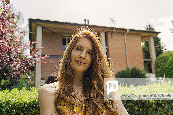 Young woman with long brown hair standing in garden on sunny day