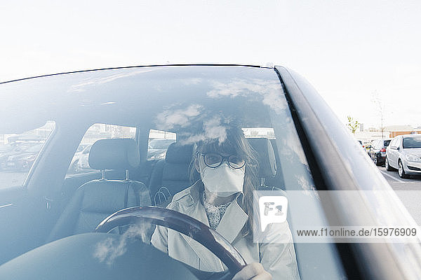 Woman wearing face mask in a car