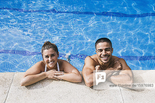 Lächelndes junges Paar im Schwimmbad stehend