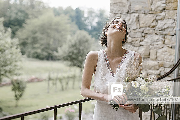 Junge lächelnde Frau in elegantem Hochzeitskleid mit Blumenstrauß