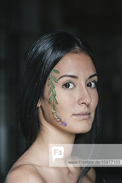 Schöne junge Frau mit Blättern im Gesicht