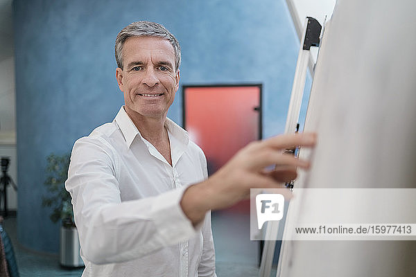 Porträt eines selbstbewussten männlichen Fachmanns  der in einer Besprechung im Büro eine Strategie am Whiteboard plant