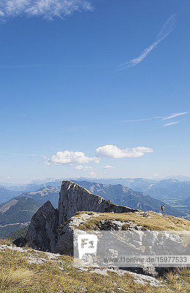 Fernansicht eines Wanderers auf dem Spinnerin-Gipfel vor blauem Himmel