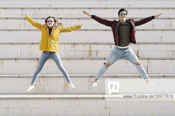 Happy young couple jumping on stairs
