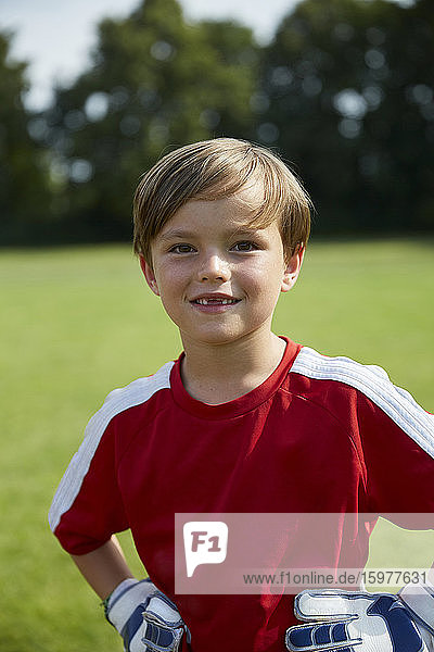 Porträt eines glücklichen Jungen im Fußballtrikot auf dem Spielfeld