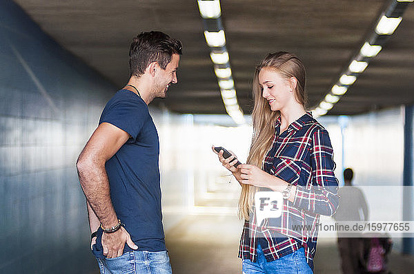 Young man and young woman standing together in an underpass