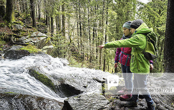 Junge und Mädchen betrachten einen Wasserfall im Nordschwarzwald