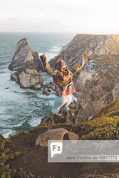 Junge Frau  die am Strand von Ursa auf einen Hügel springt  Region Lisboa  Portugal