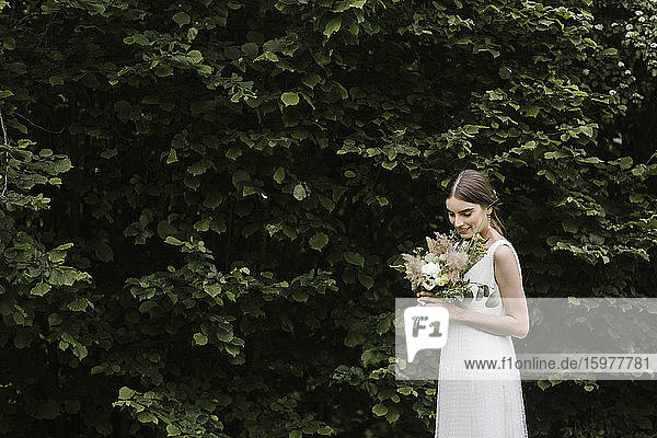 Junge Frau in elegantem Hochzeitskleid und Blumenstrauß