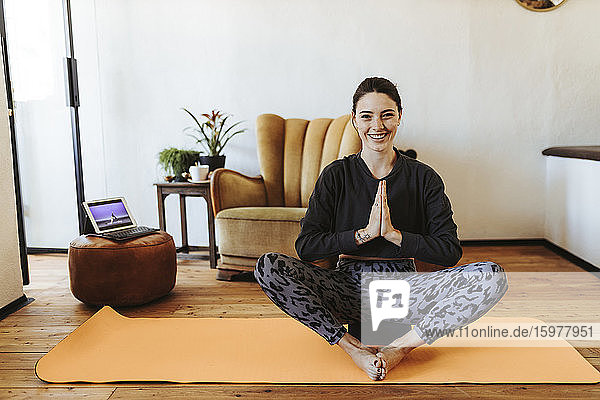 Portrait of happy yYoung woman practicing yoga at home