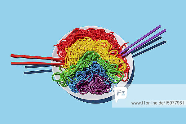 Plate of rainbow-colored spaghetti against blue background