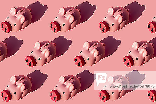 Seamless pattern of rows of piggy banks against pastel pink background
