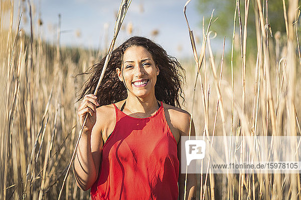 Portrait of happy young woman among reed