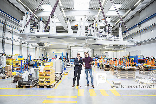 Two men with indoor crane in a factory