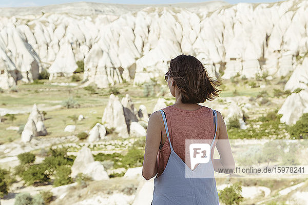Rückansicht einer jungen Frau mit Blick auf die felsige Landschaft im Dorf Goreme  Kappadokien  Türkei