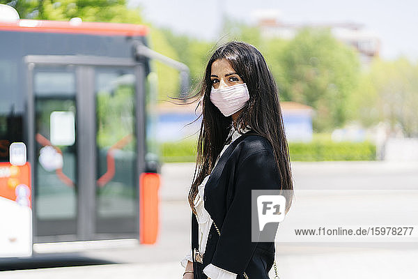 Porträt einer jungen Frau mit Schutzmaske  die an einer Bushaltestelle wartet  Spanien