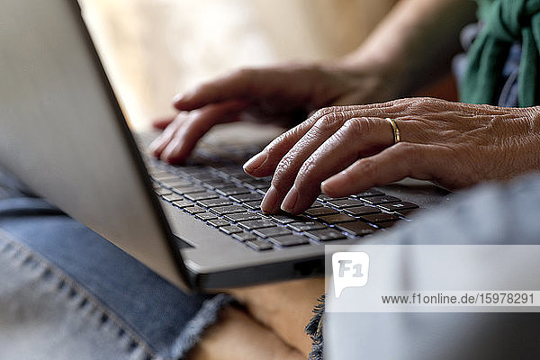 Reife Frau benutzt Laptop bei der Arbeit zu Hause während der Ausgangssperre