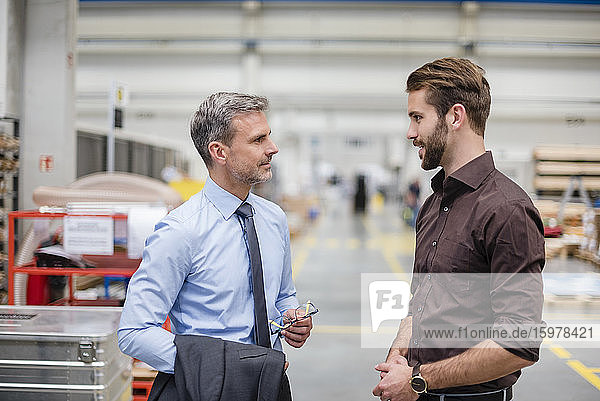Zwei Geschäftsleute unterhalten sich in einer Fabrik
