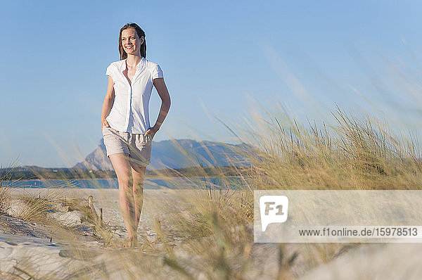 Porträt einer lächelnden Frau  die in den Stranddünen spazieren geht  Sardinien  Italien