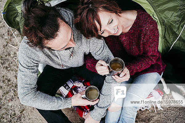 Happy couple holding mugs at a tent