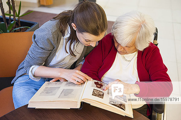 Großmutter mit Enkelin beim Betrachten eines Fotoalbums zu Hause