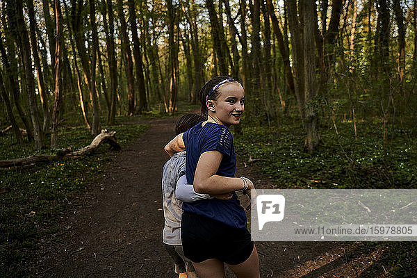 Lächelndes Mädchen mit Arm um Bruder im Wald