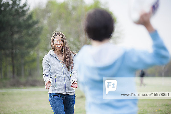 Happy woman playing rugby with son in park