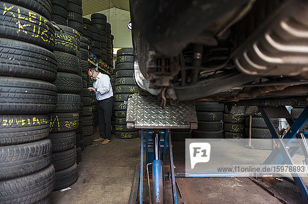 Senior male entrepreneur standing by tire stacks at store