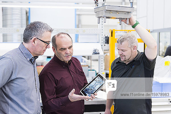 Three men with tablet having a discussion in a factory