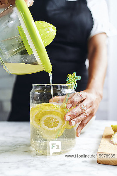 Hands of woman preparing fresh lemonade