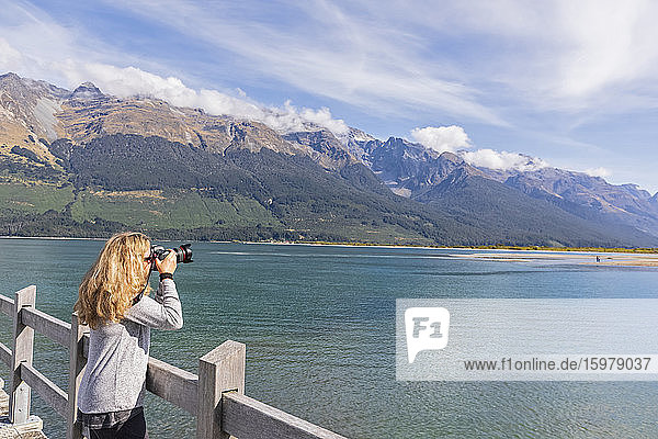 New Zealand  Oceania  South Island  Otago  Lake Wakatipu  New Zealand Alps  Glenorchy  Woman photographing landscape from pier