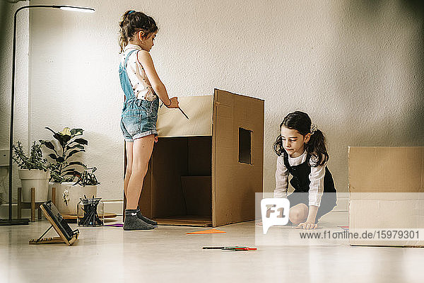 Zwei kleine Schwestern bauen Haus mit Karton