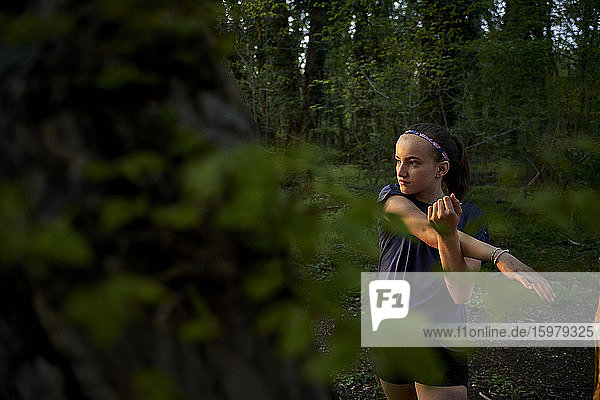 Mädchen schaut weg  während sie sich streckt und im Wald steht