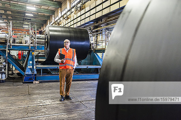 Senior man wearing safety vest in a rubber processing factory