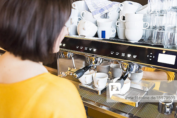 Weibliche Barista mit Espressomaschine in einem Kaffeegeschäft