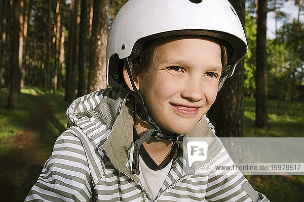 Glücklicher Junge mit Fahrradhelm im Wald